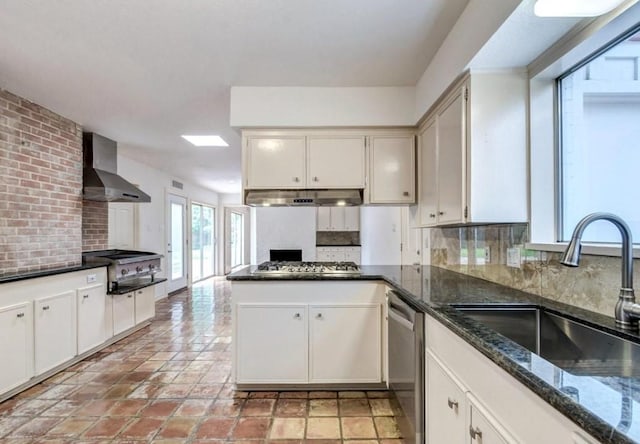 kitchen featuring sink, white cabinets, decorative backsplash, wall chimney range hood, and appliances with stainless steel finishes