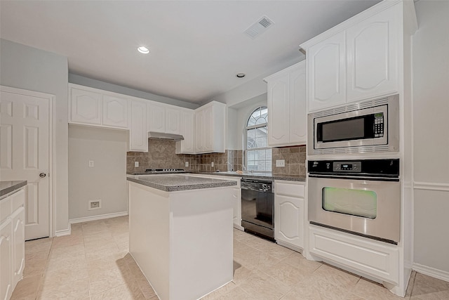 kitchen featuring white cabinets, appliances with stainless steel finishes, a kitchen island, backsplash, and light tile patterned floors