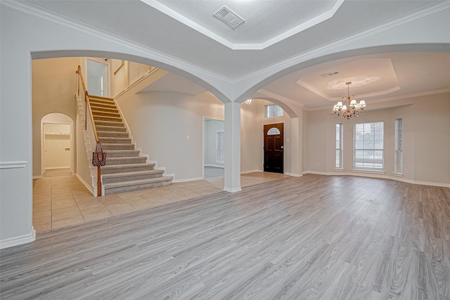 entryway with a chandelier, light hardwood / wood-style floors, a raised ceiling, and ornamental molding