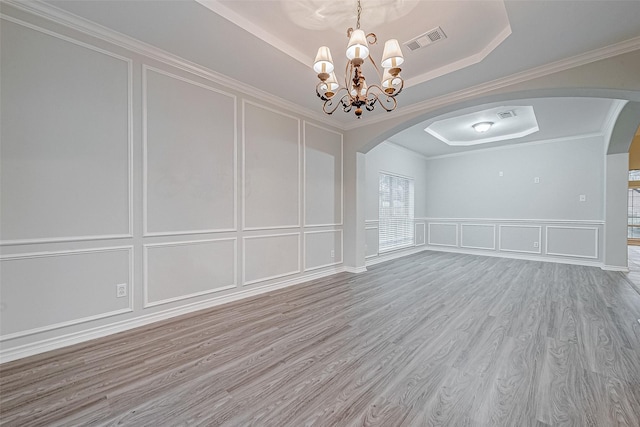 spare room with hardwood / wood-style flooring, a tray ceiling, ornamental molding, and a notable chandelier