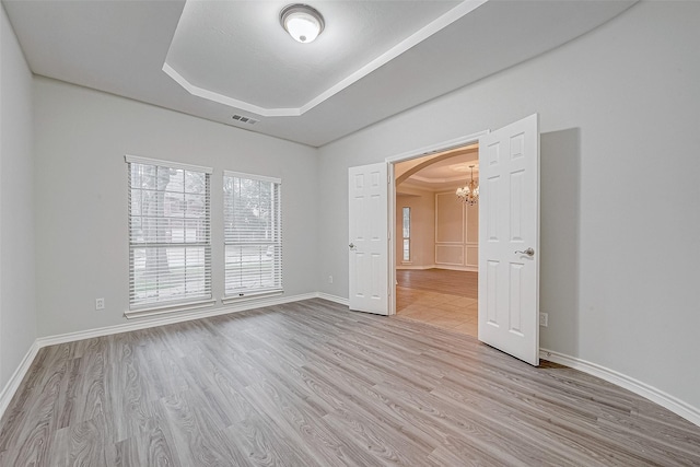 unfurnished bedroom with a raised ceiling and light wood-type flooring