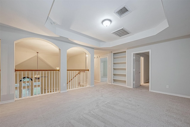 carpeted spare room with built in shelves and a tray ceiling