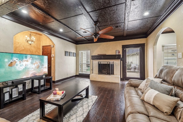 living room with ceiling fan with notable chandelier, wood-type flooring, ornamental molding, and coffered ceiling