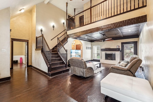 living room featuring ceiling fan, a high ceiling, beamed ceiling, and hardwood / wood-style flooring