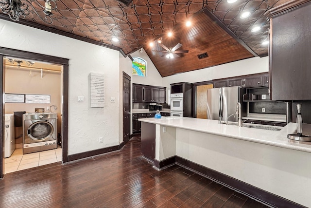 kitchen with kitchen peninsula, stainless steel fridge, ceiling fan, washing machine and clothes dryer, and dark brown cabinetry