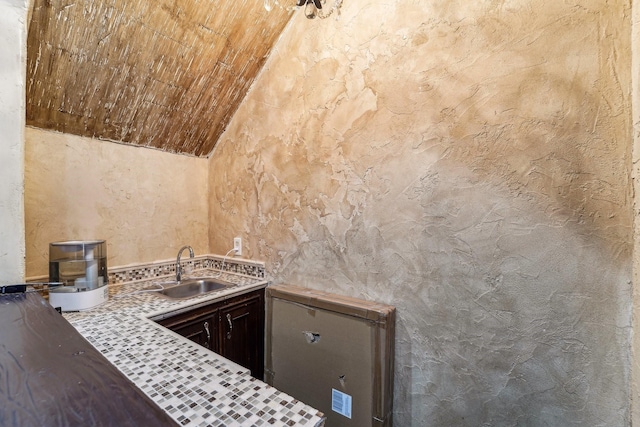 kitchen featuring sink, lofted ceiling, and dark brown cabinets