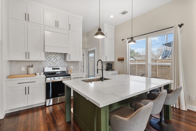 kitchen featuring light stone countertops, white cabinets, decorative light fixtures, sink, and stainless steel range with gas cooktop