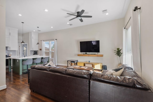 living room featuring dark wood-type flooring, sink, and ceiling fan