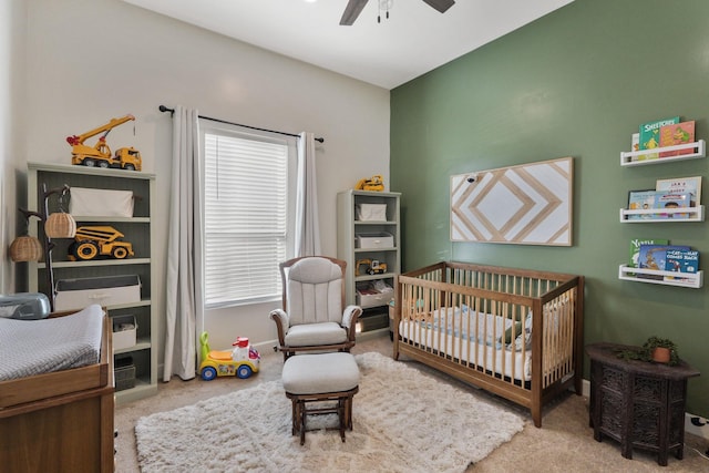 carpeted bedroom featuring ceiling fan and a crib