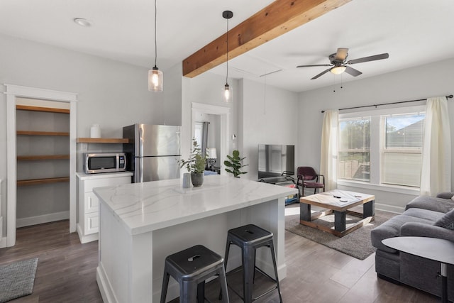 kitchen featuring appliances with stainless steel finishes, dark wood-type flooring, hanging light fixtures, light stone counters, and beam ceiling