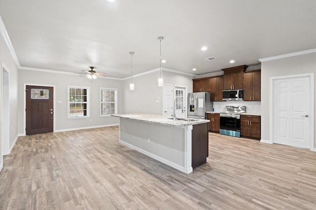 kitchen featuring ceiling fan, appliances with stainless steel finishes, ornamental molding, and a kitchen island with sink