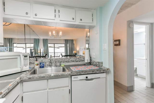 kitchen with white appliances, a chandelier, decorative backsplash, white cabinets, and sink