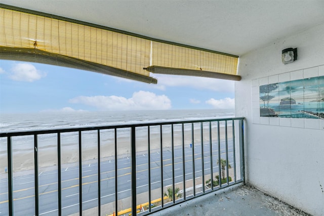 balcony featuring a view of the beach and a water view