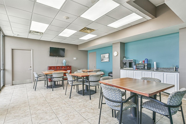 tiled dining room featuring a drop ceiling