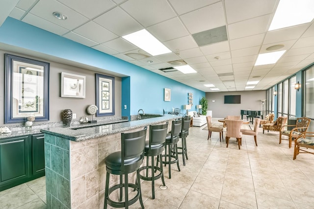 bar with a paneled ceiling and dark stone countertops