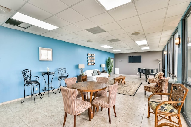 dining space with a drop ceiling and light tile patterned floors