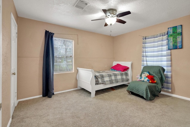 bedroom with light colored carpet, ceiling fan, and a textured ceiling