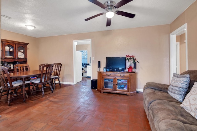 living room featuring dark parquet flooring, a textured ceiling, and ceiling fan