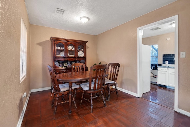 dining area with dark parquet flooring and a textured ceiling