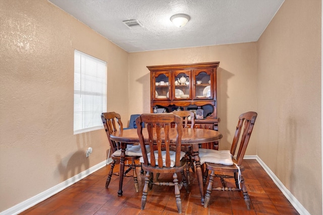 dining area featuring dark parquet flooring and a textured ceiling