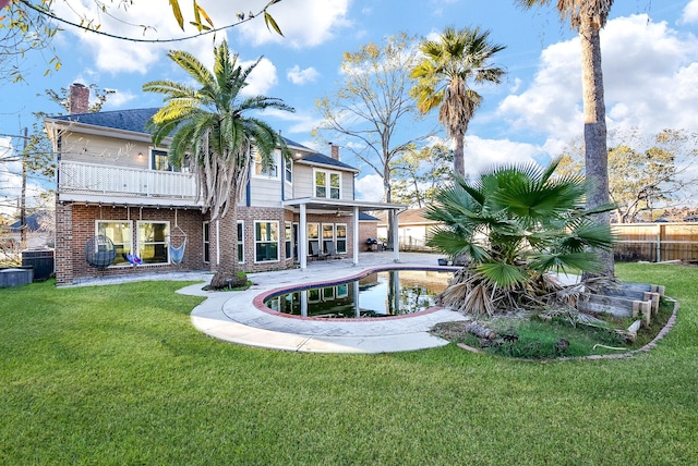 rear view of house with a fenced in pool, a patio, a balcony, and a yard