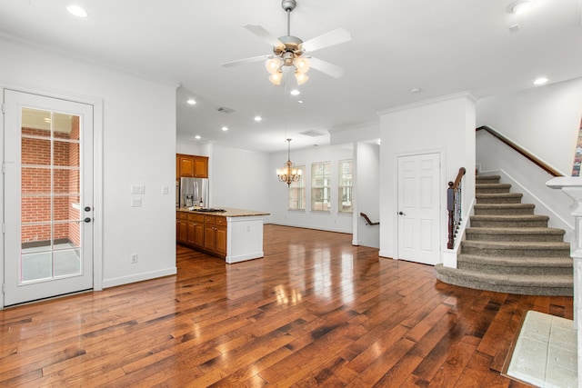 kitchen featuring dark wood-type flooring, stainless steel fridge, a kitchen island, crown molding, and ceiling fan with notable chandelier