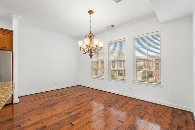 unfurnished dining area featuring an inviting chandelier, ornamental molding, and hardwood / wood-style floors