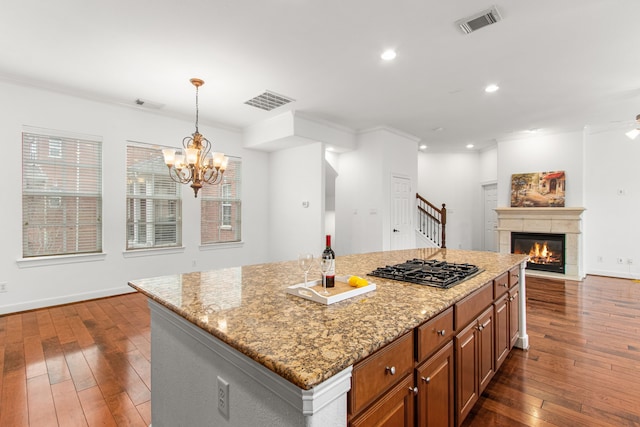 kitchen featuring dark wood-type flooring, ornamental molding, hanging light fixtures, and a center island