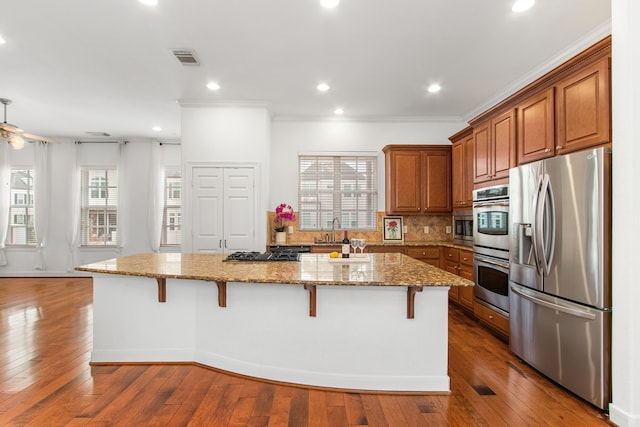 kitchen featuring light stone countertops, a kitchen island, a breakfast bar area, and appliances with stainless steel finishes