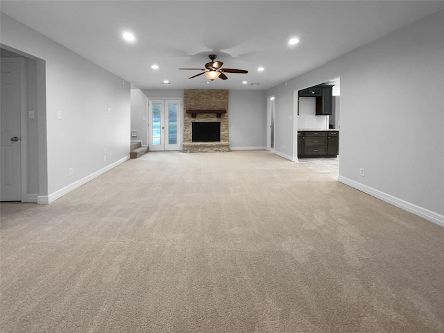 unfurnished living room featuring a fireplace, ceiling fan, and light colored carpet