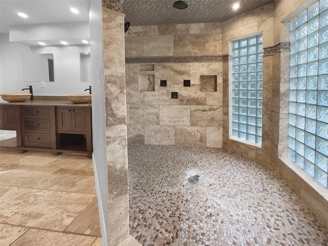 bathroom featuring tile walls, tiled shower, and vanity