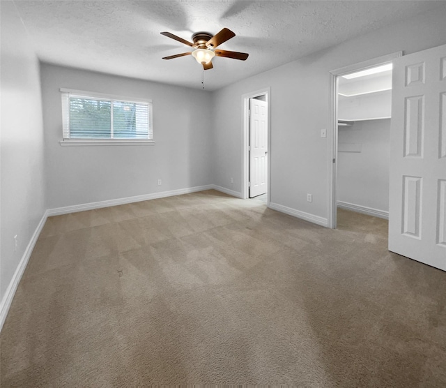 unfurnished room featuring ceiling fan, light colored carpet, and a textured ceiling