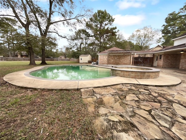 view of swimming pool featuring a storage shed, a patio area, and an in ground hot tub