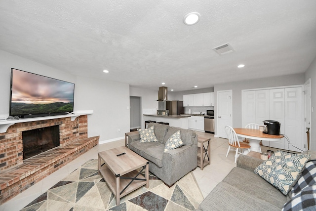 tiled living room with a textured ceiling and a brick fireplace