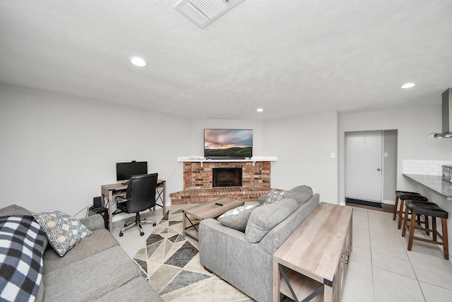 tiled living room featuring a textured ceiling and a brick fireplace