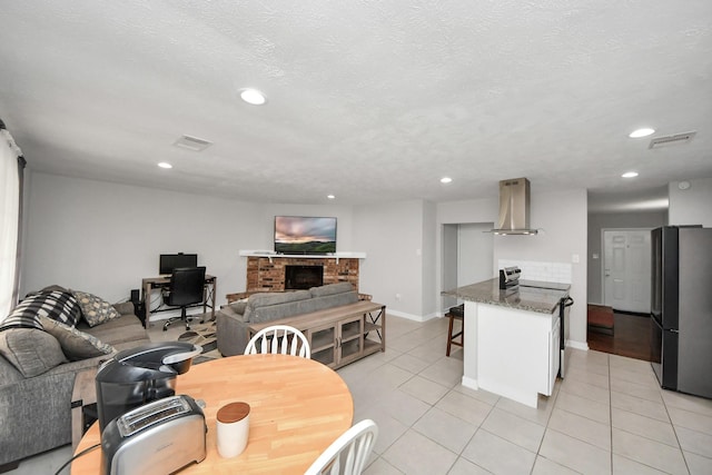 tiled dining area featuring a textured ceiling and a brick fireplace