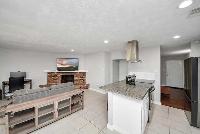 kitchen with stone countertops, island exhaust hood, stainless steel appliances, and light tile patterned flooring