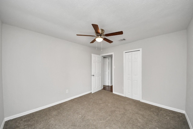 unfurnished bedroom with a textured ceiling, ceiling fan, a closet, and dark colored carpet