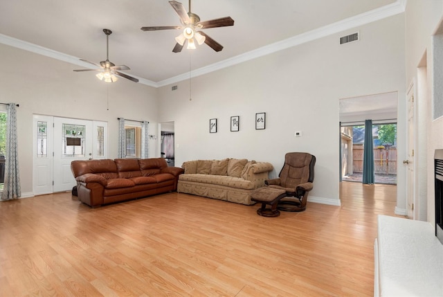 living room featuring ceiling fan, light hardwood / wood-style flooring, a towering ceiling, and crown molding