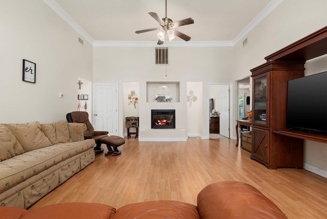 living room featuring ceiling fan, ornamental molding, and wood-type flooring