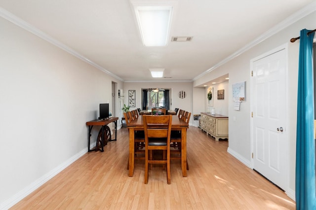 dining room with light hardwood / wood-style floors and crown molding