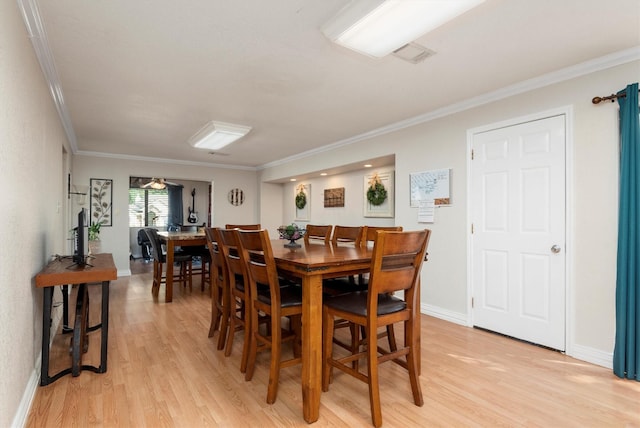 dining space featuring ornamental molding and light hardwood / wood-style flooring