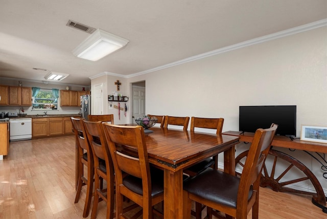 dining room featuring light wood-type flooring, ornamental molding, and sink