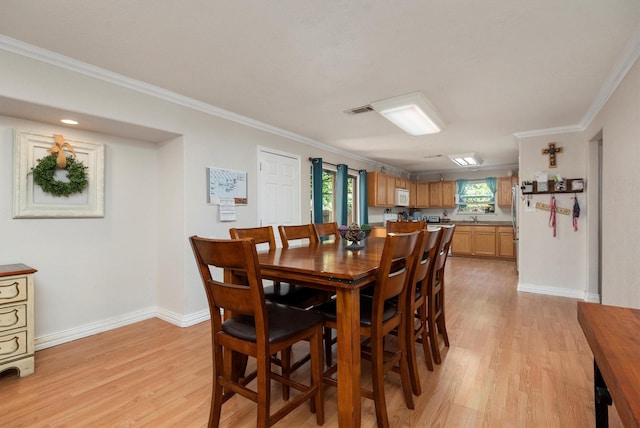 dining space featuring light hardwood / wood-style floors, crown molding, and sink