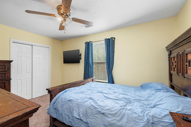 carpeted bedroom featuring ceiling fan, a closet, and a textured ceiling