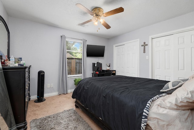 bedroom featuring two closets, ceiling fan, and carpet