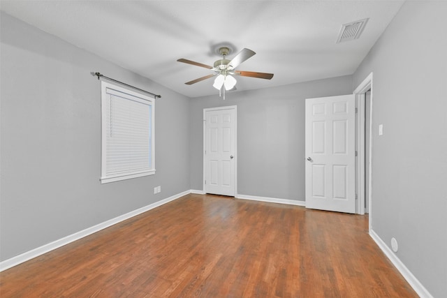 unfurnished bedroom with ceiling fan and dark wood-type flooring