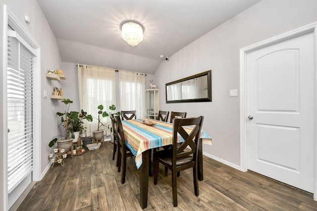 dining space with lofted ceiling, a notable chandelier, and dark wood-type flooring