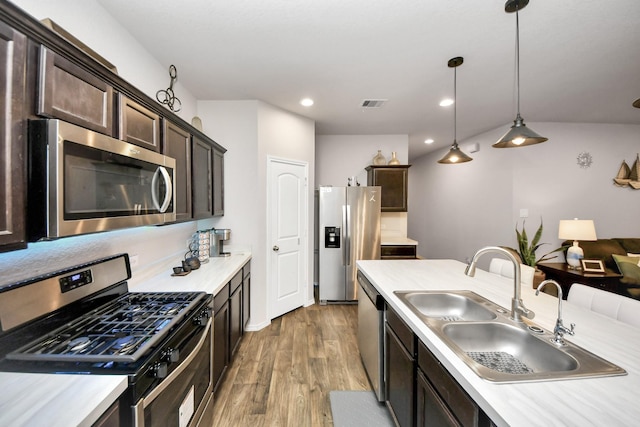 kitchen with appliances with stainless steel finishes, dark brown cabinets, decorative light fixtures, and sink