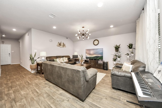 living room with an inviting chandelier, vaulted ceiling, and light hardwood / wood-style flooring